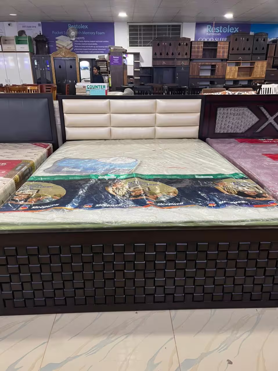 King size bed with white padded cushion headboard and dark wood storage base.